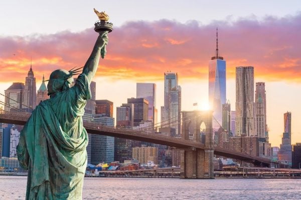 statue liberty and new york city skyline at sunset
